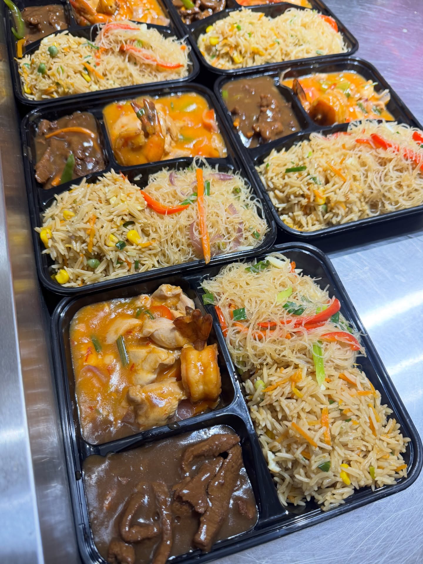 Catering compartment trays lined up — ofada rice packs with ayamase